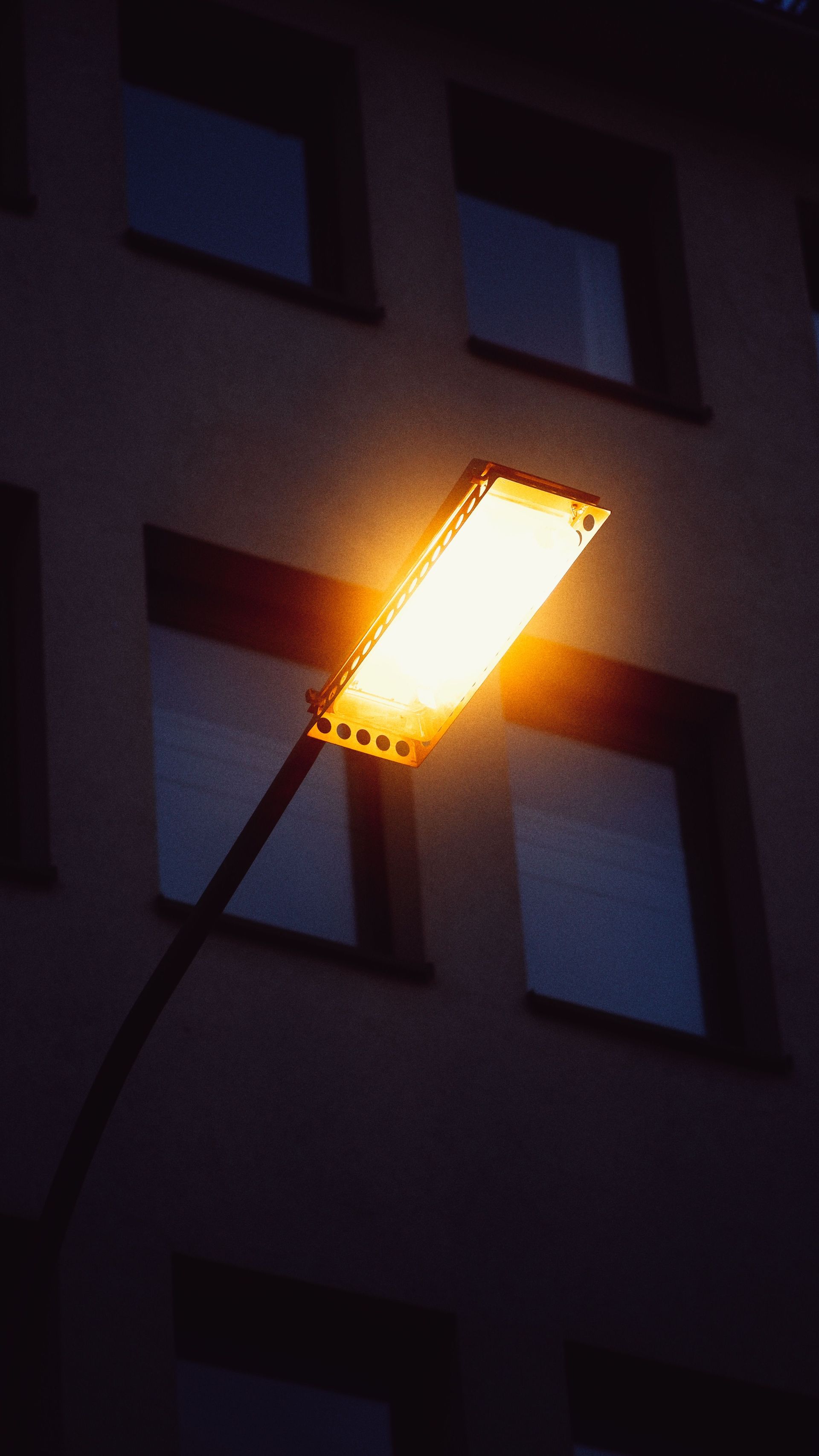 Close-up of a bright streetlight casting a warm glow against a building background.