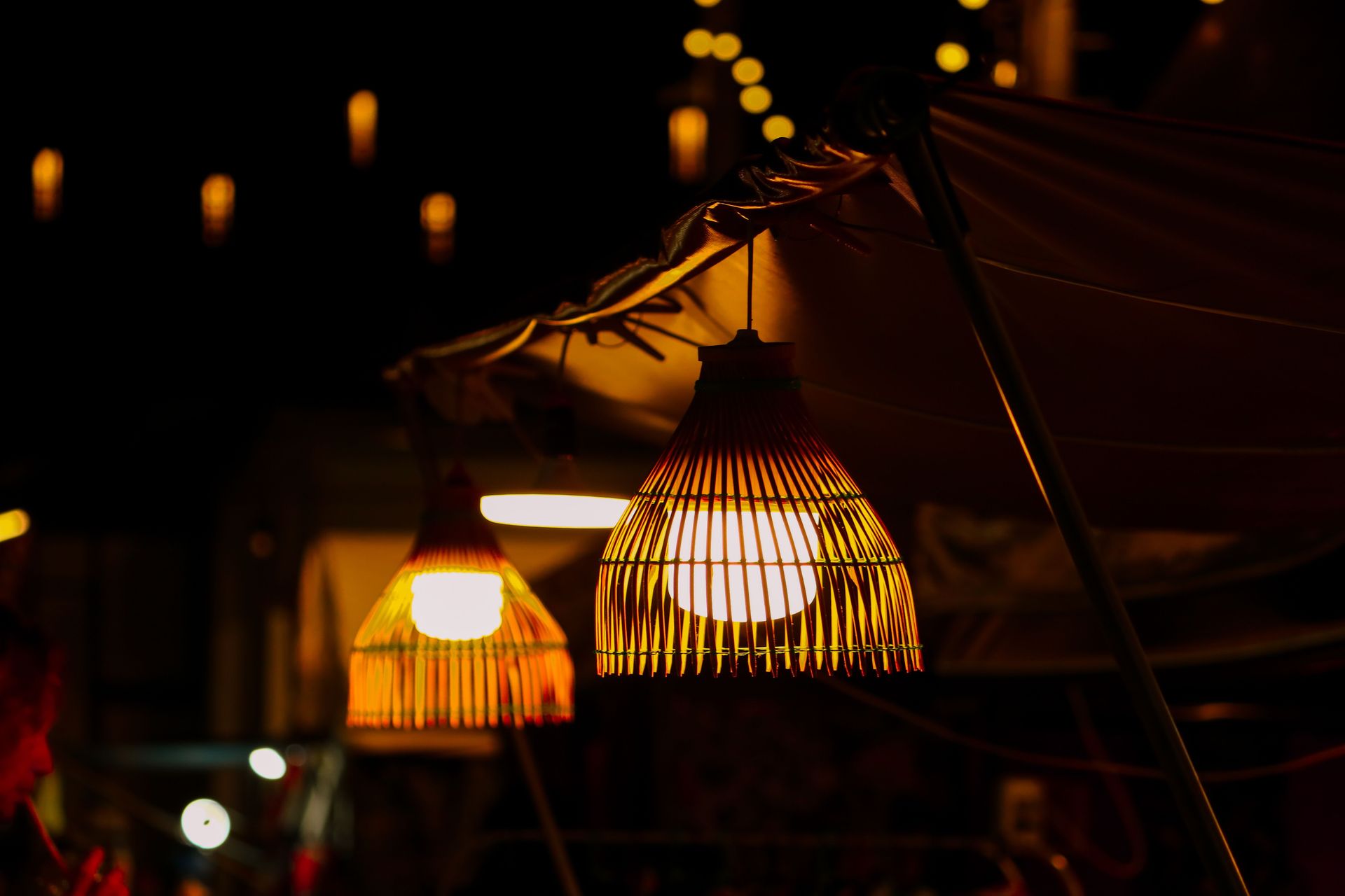 Warm light from woven lanterns at a night market, creating a cozy atmosphere.