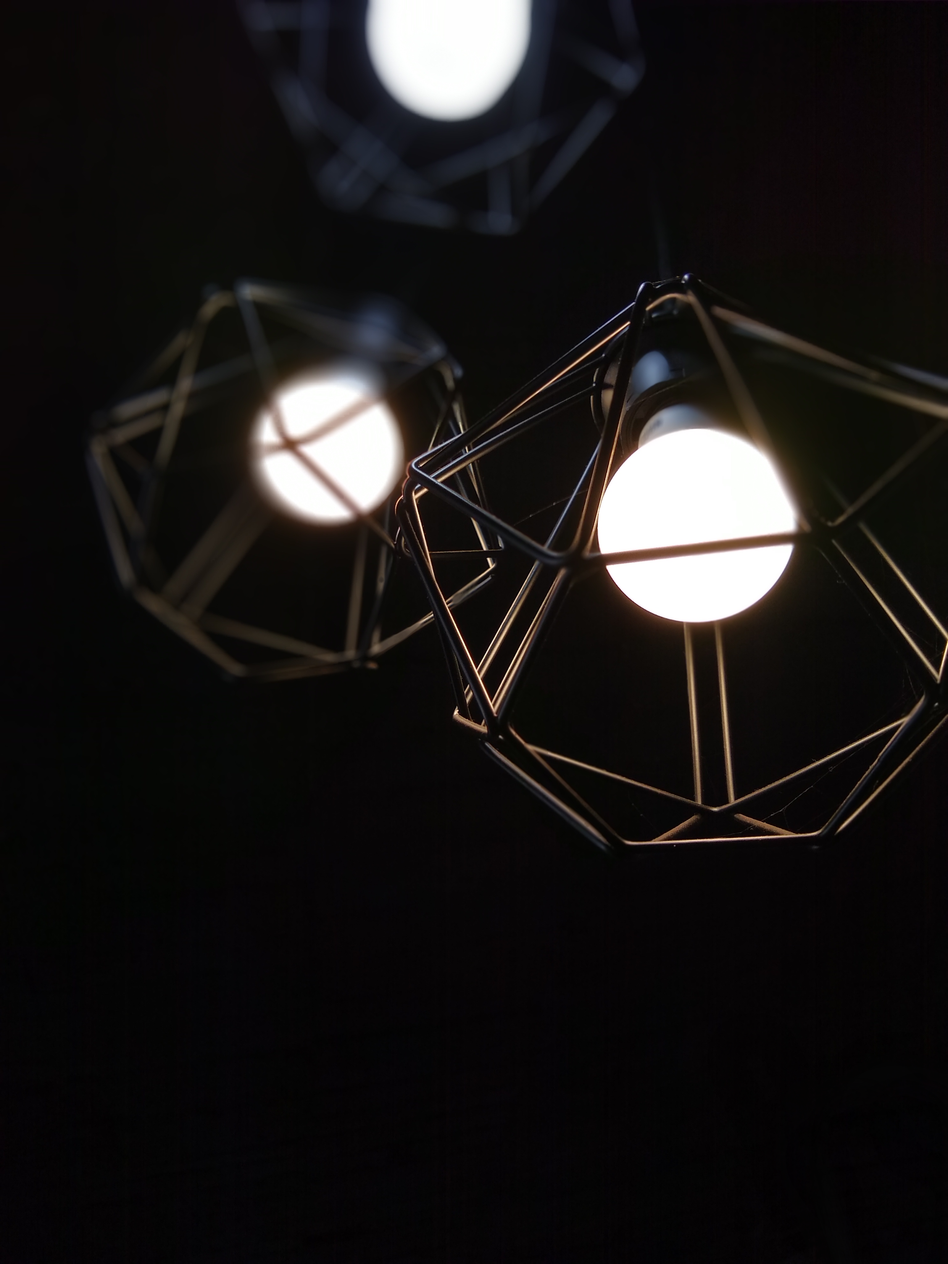 Stylish geometric pendant lights with soft glowing bulbs, ideal for contemporary interiors.