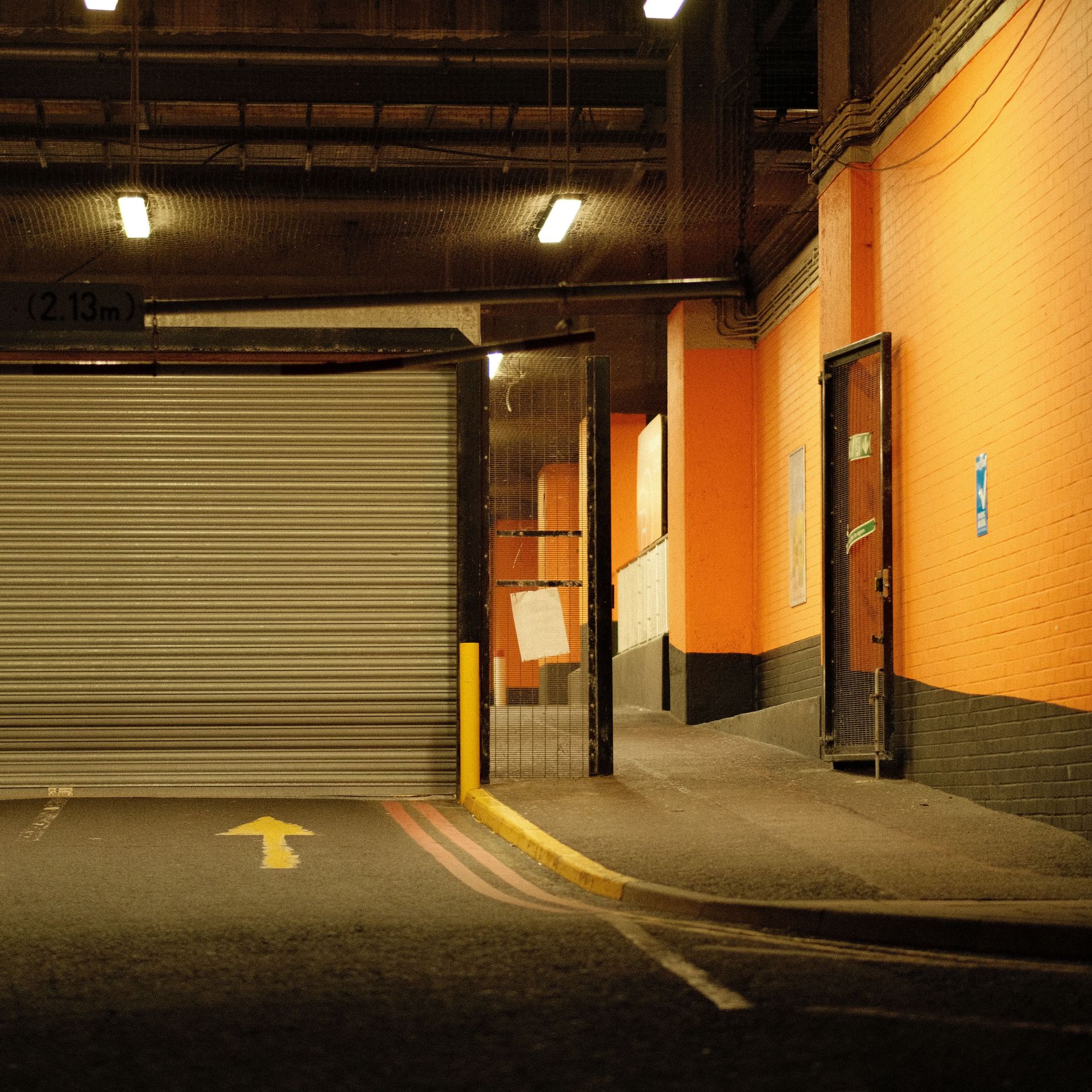 Moody urban parking garage scene with a closed gate and vibrant walls, highlighting the gritty ambiance.