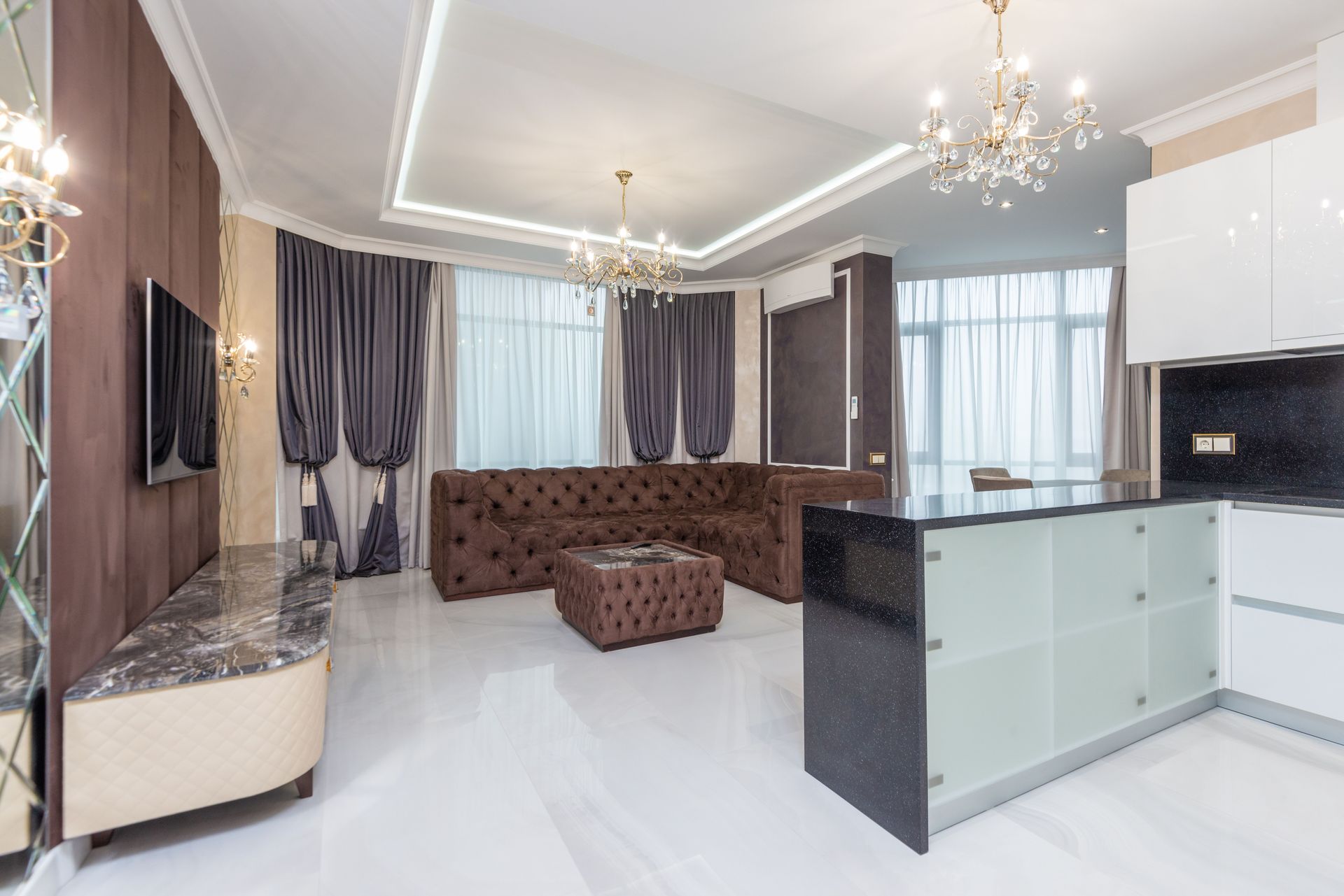 Spacious modern living room featuring elegant chandeliers, plush sofa, and contemporary decor.